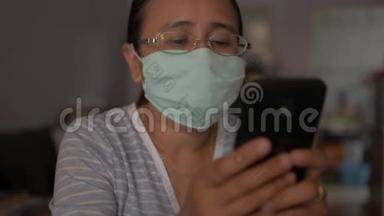妇女戴着保护面具，同时在家里使用手机，在COVID-19疫情期间。 冠状病毒保护。